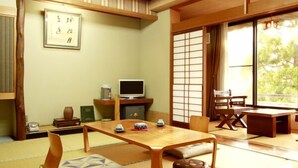 Perinteinen japanilainen huone, jossa on tatamimatto, matala pöytä, televisio ja liukuvat ovet.
