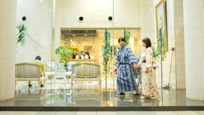 A lobby with a glass partition, seating area, and decorative plants. - Hotel AreaOne Hiroshima Wing (Higashihiroshima)