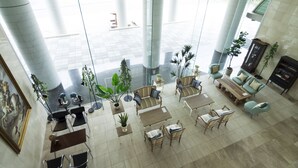 A spacious lobby with high ceilings, large windows, and a central seating area with sofas and tables. - Hotel AreaOne Hiroshima Wing (Higashihiroshima)
