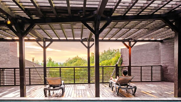 A covered outdoor pool area with two lounge chairs and a view of greenery. - Hotel AreaOne Hiroshima Wing (Higashihiroshima)