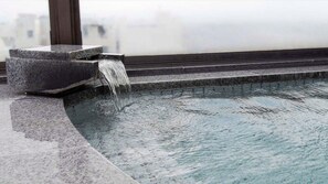 A stone water feature with a cascading waterfall, a pool, and steps leading to a balcony. - Tokyo Dai-ichi Hotel Tsuruoka (Tsuruoka)