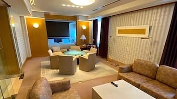 Una moderna camera d'hotel con angolo salotto, TV a schermo piatto e un'ampia finestra.