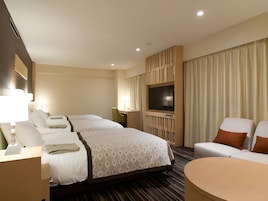 A hotel room with a large bed, a TV, a desk, and a seating area.
