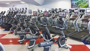 A gym with multiple treadmills and elliptical machines, each equipped with a digital display.