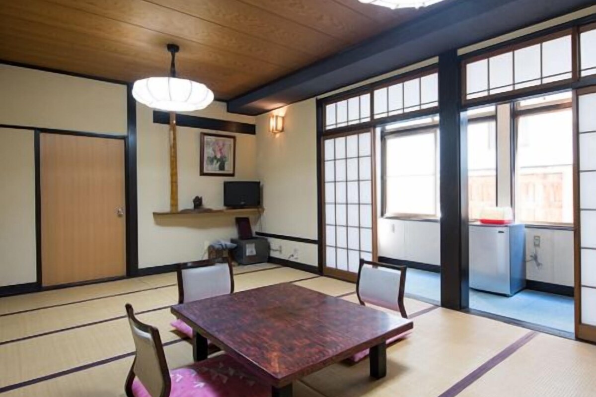 Ein traditioneller japanischer Raum mit Tatami-Boden, einem niedrigen Tisch und Schiebetüren.