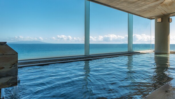 Una piscina infinita moderna con agua azul cristalina, amplias ventanas de vidrio y vista al océano.