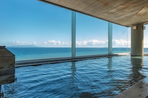 A modern infinity pool with clear blue water, large glass windows, and a view of the ocean. - Atagawakan (Higashiizu)