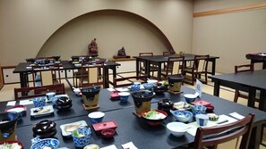 A traditional Japanese dining room with multiple tables set with various dishes and utensils.