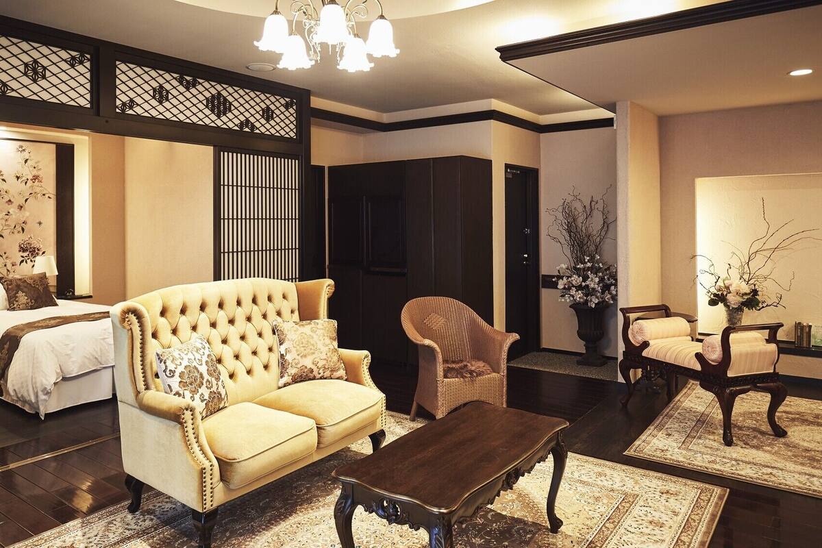 Quarto japonês tradicional com tatames, um sofá baixo, mesa de centro de madeira e uma porta de correr.