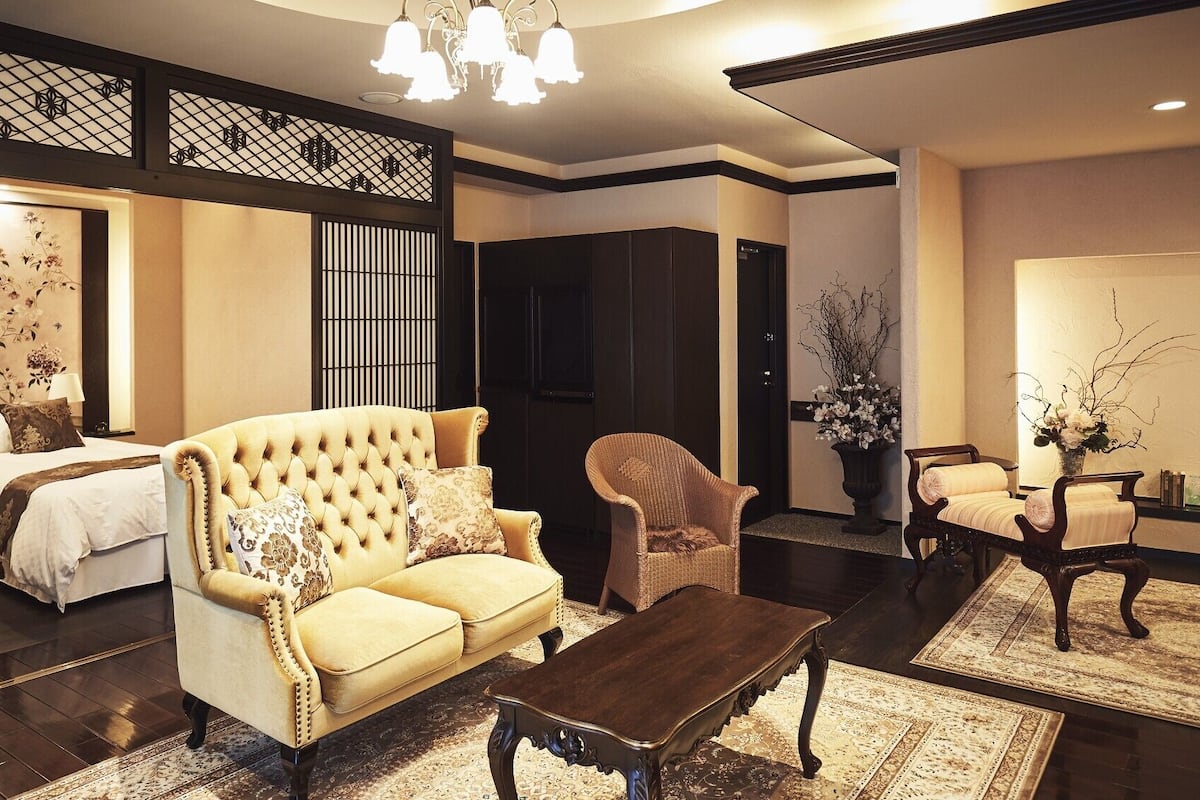 A traditional Japanese-style room with tatami flooring, a low sofa, a wooden coffee table, and a sliding door.