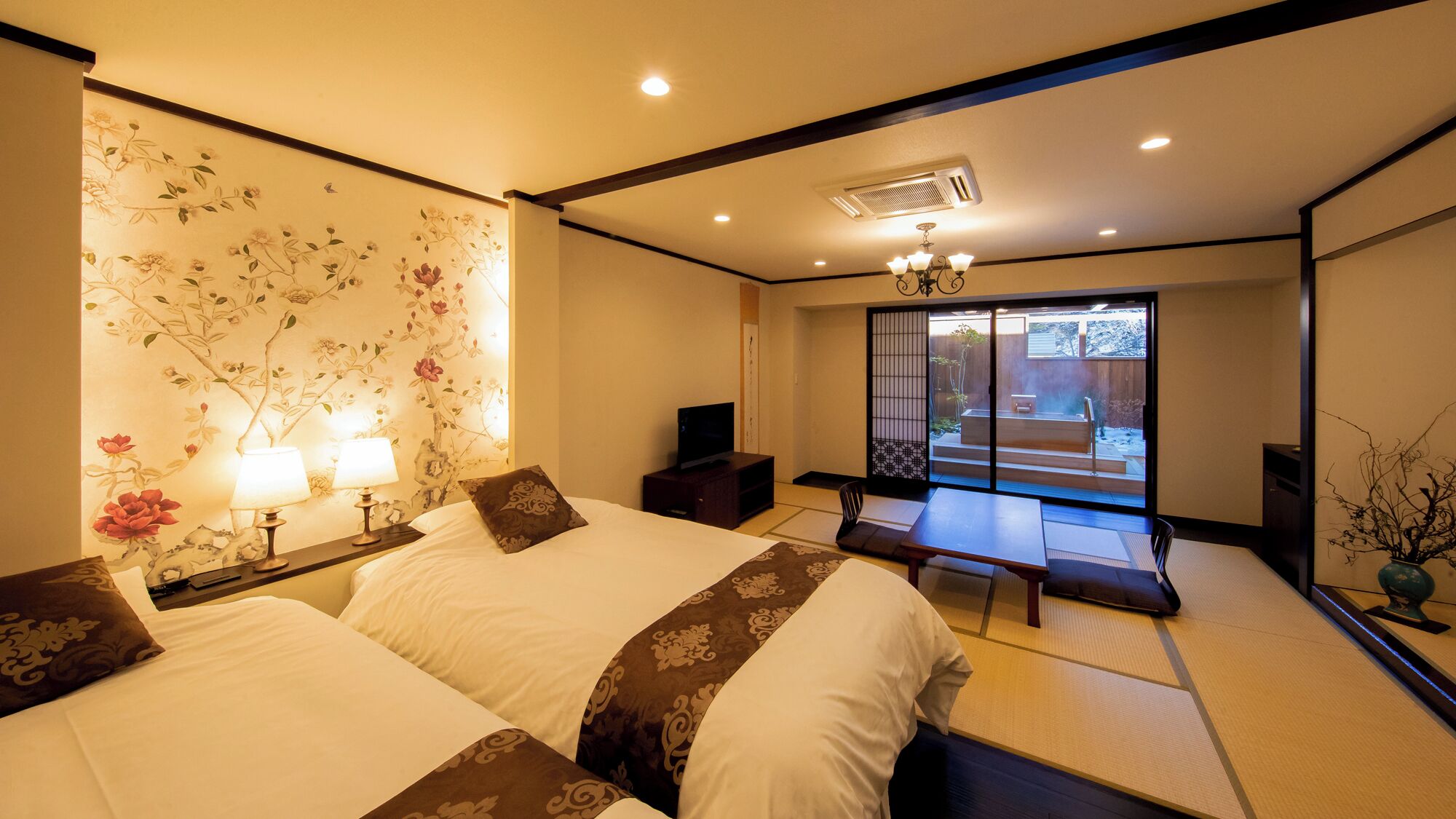 A traditional Japanese-style room with tatami flooring, a sliding door leading to a balcony, and a television on a low table.