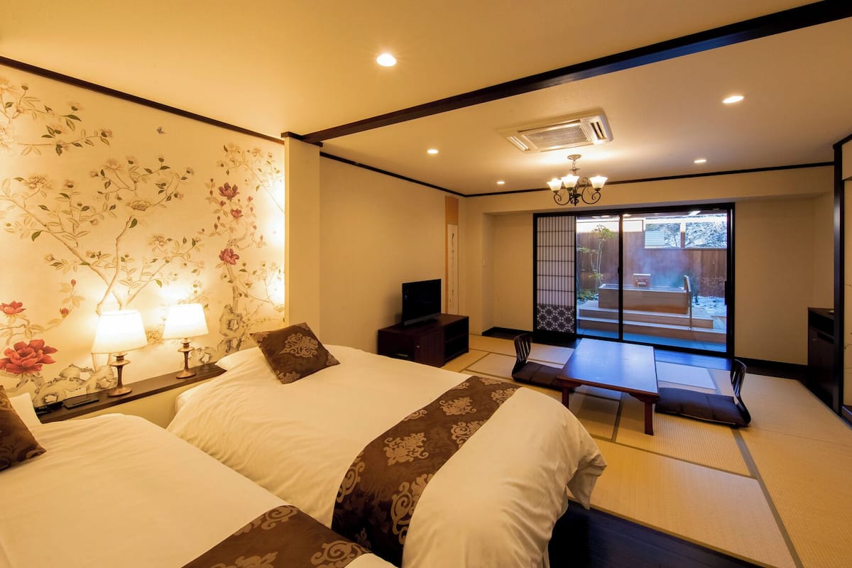 A traditional Japanese-style room with tatami flooring, a sliding door leading to a balcony, and a television on a low table.