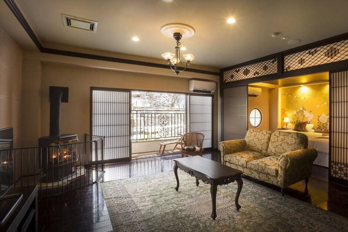 Quarto tradicional com tatame, um sofá, uma mesa, lareira e um biombô shoji.