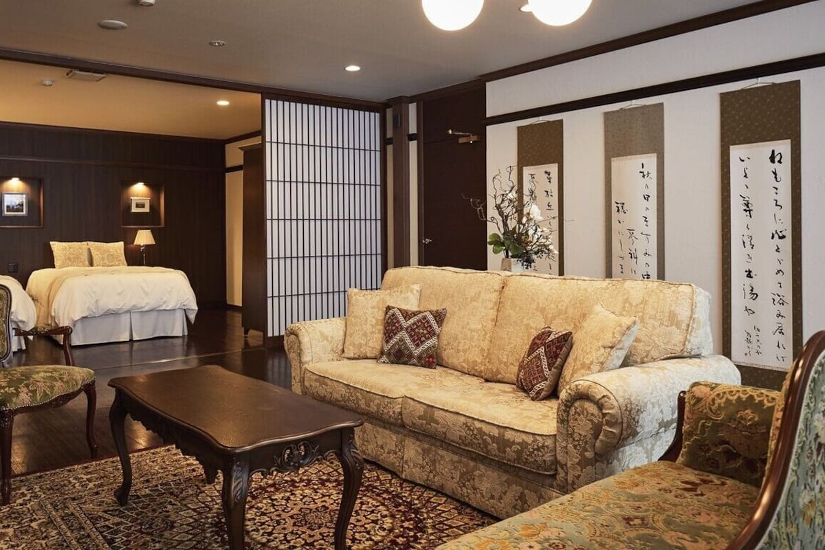 A hotel room with a sofa, two chairs, a coffee table, and a bed.