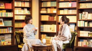 Dos personas sentadas en una biblioteca con estanterías llenas de libros.