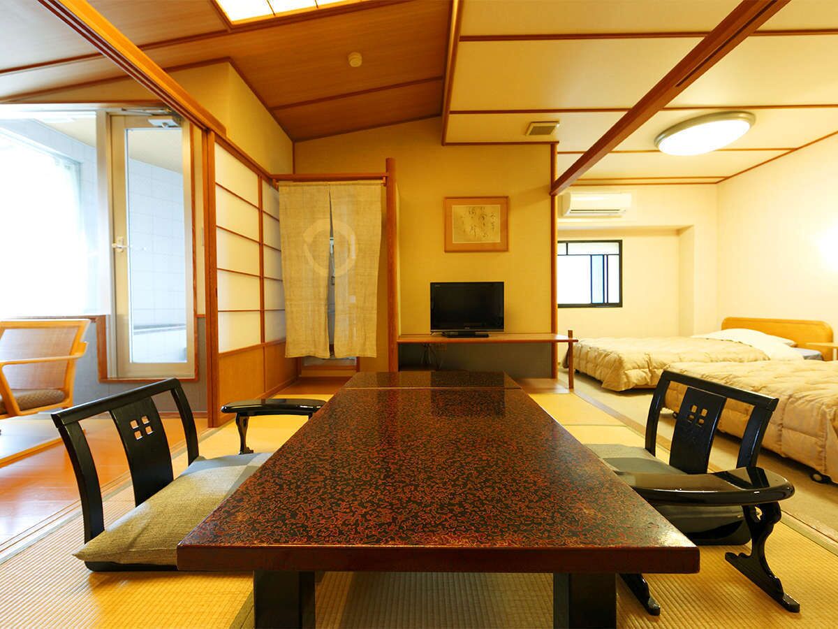 Um quarto japonês tradicional com tatames, uma mesa baixa e uma cama.