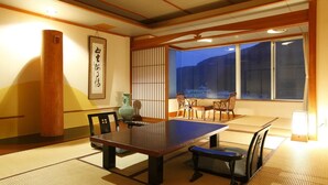 A traditional Japanese room with tatami flooring, a low table, and chairs. - Tokiwaya (Numazu)