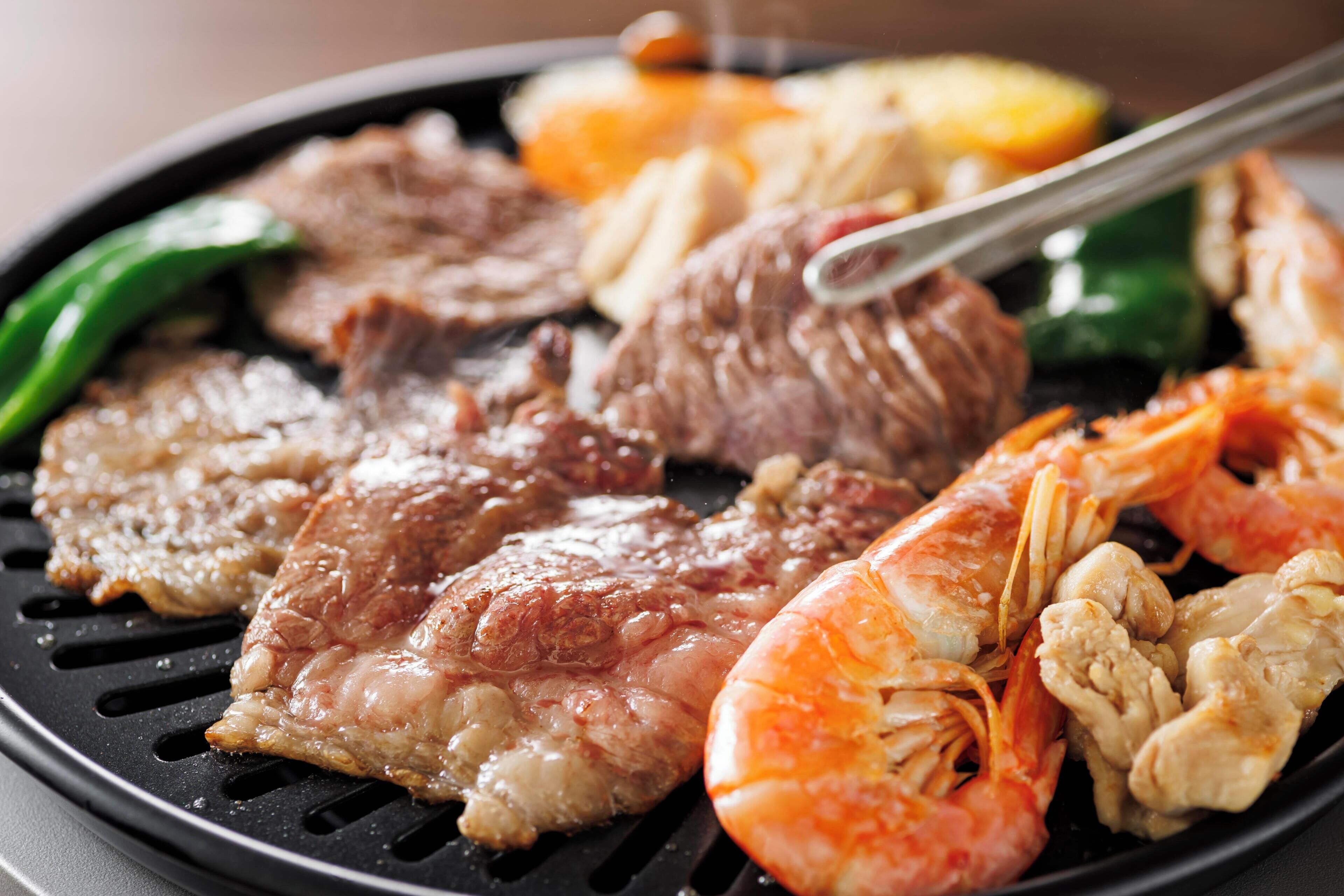 A grill with various meats and shrimp.
