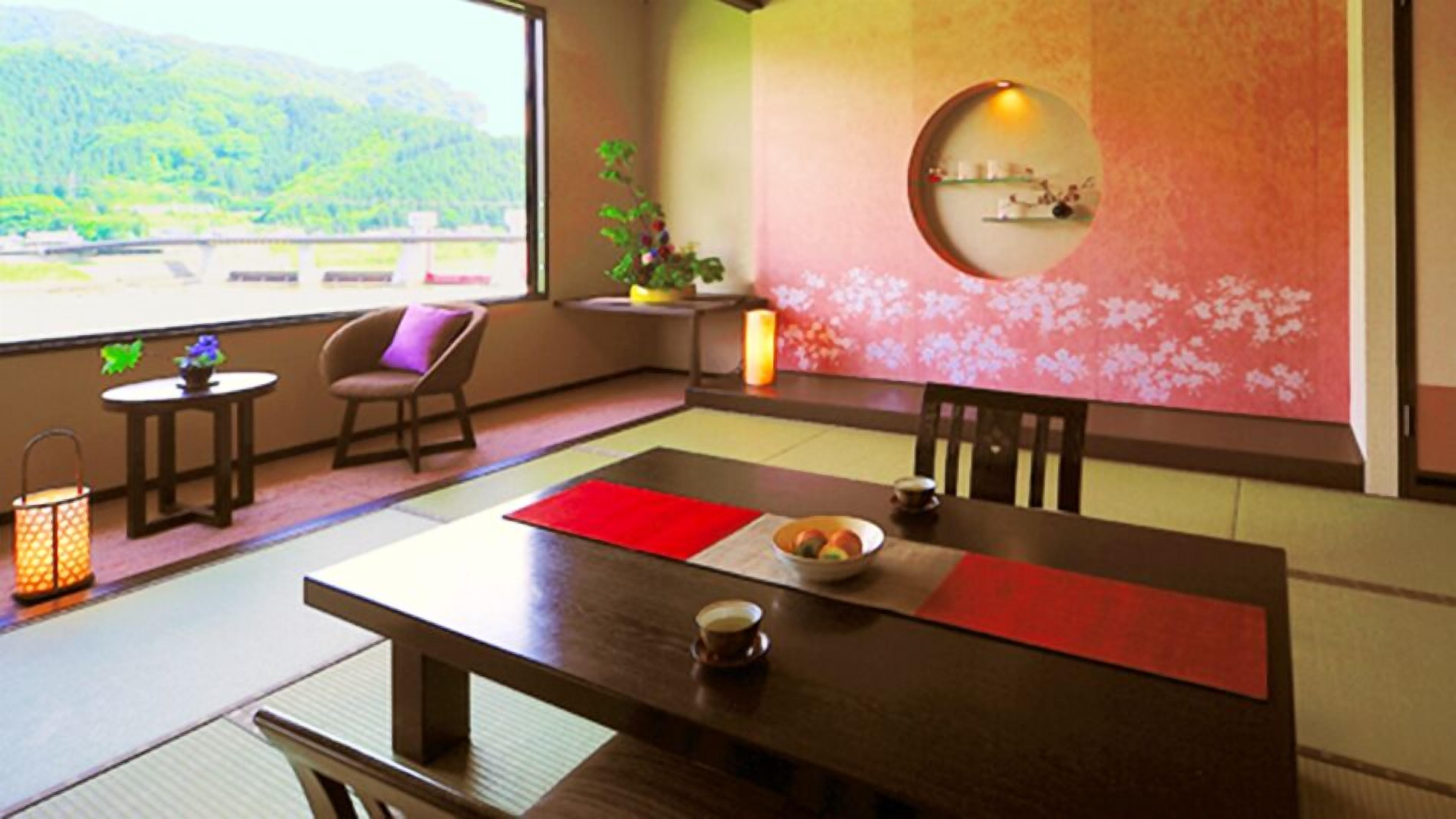 A traditional Japanese-style room with tatami flooring, a low table with a red placemat, a bowl of fruit, and a small candle.