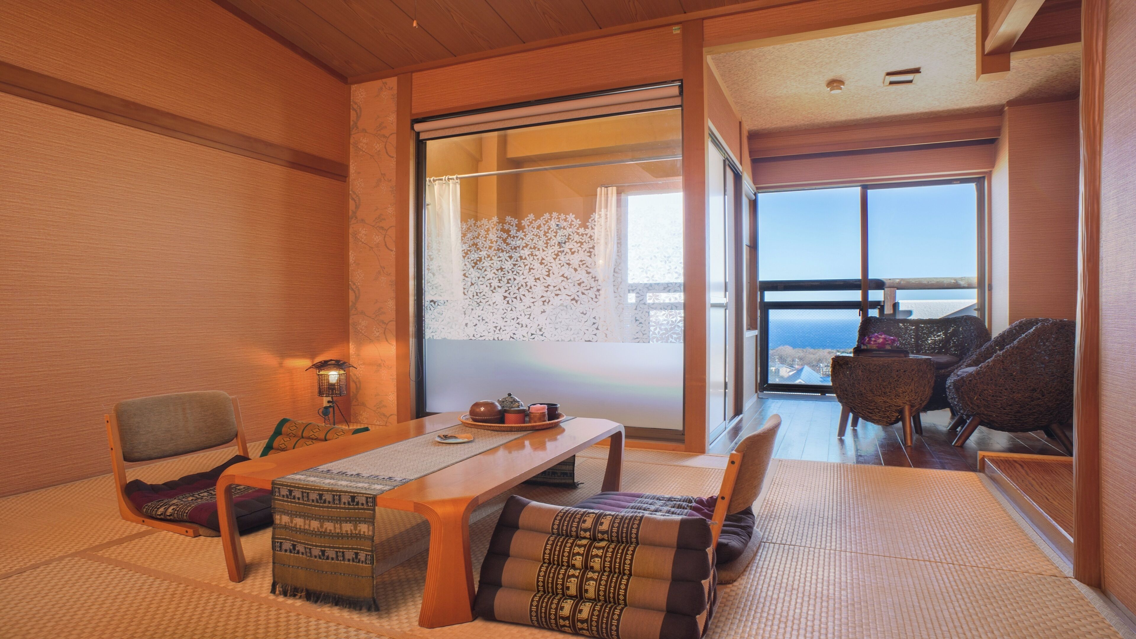 Una habitación tradicional japonesa con suelo de tatami, una mesa baja y vistas al mar a través de amplios ventanales.