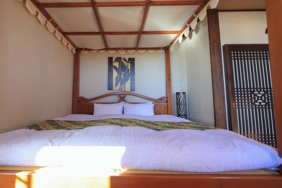 Un lit avec une tête de lit en bois, une couvre-lit à motifs et un tableau au-dessus du lit.