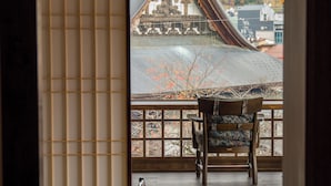 Ein traditioneller japanischer Raum mit Tatami-Böden, einem niedrigen Holztisch und Blick auf einen Tempel durch einen Shoji-Bildschirm.