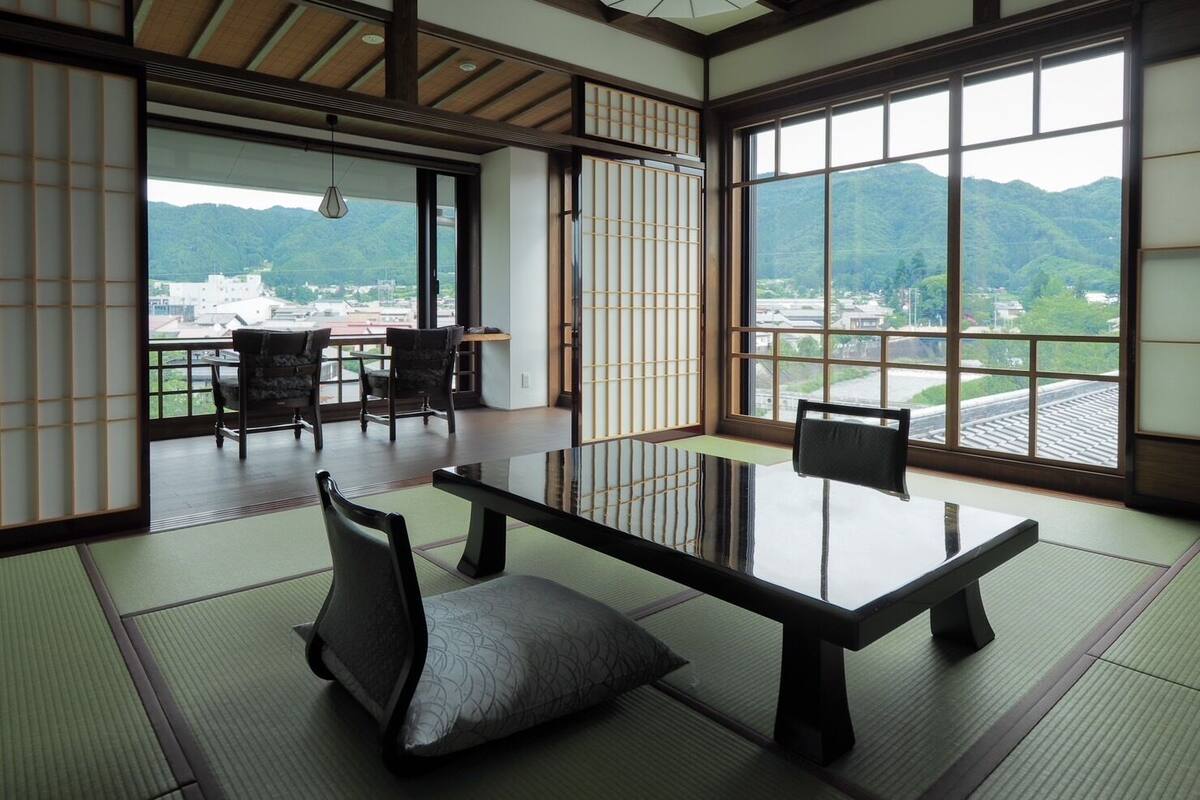 Une pièce de style japonais traditionnel, avec un sol recouvert de tatamis, une table basse et des chaises.