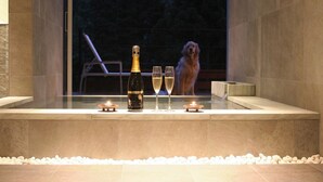 Una bañera con una botella de champán, dos copas y una vela.