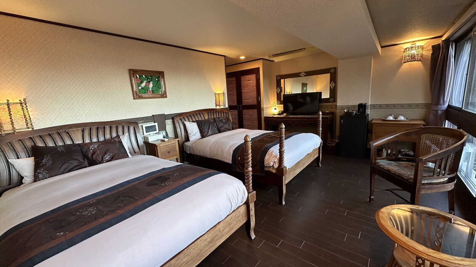 A hotel room with two beds, a desk, a chair, and a television.
