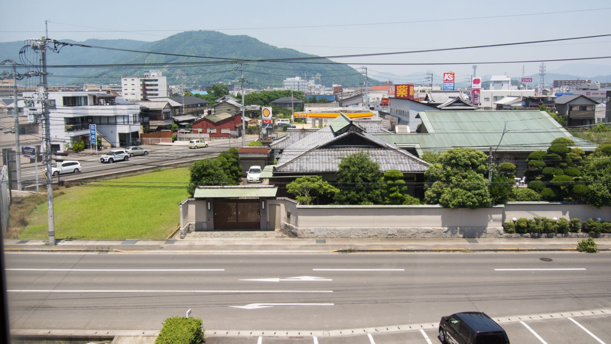 A view of a cityscape with traditional and modern buildings, a railway track, and a road with vehicles.