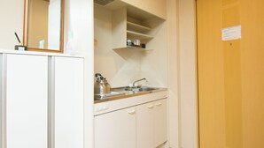 A kitchenette with a sink, kettle, and cabinets.