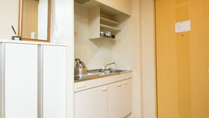 Een kitchenette met een spoelbak, waterkoker en kastjes.