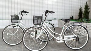 Two bicycles parked against a tiled wall with a metal fence and greenery in the background. - Hotel Matsuyama Hills (Matsuyama)