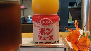 Een tafel met een fles sinaasappelsap, een theeglas en een bord met Japanse tekst.