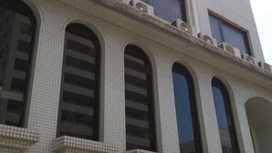 A multi-story building with a tiled facade, large arched windows, and air conditioning units on the exterior. - Hotel Matsuyama Hills (Matsuyama)