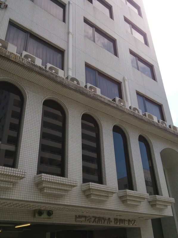 A multi-story building with a tiled facade, large arched windows, and air conditioning units on the exterior.