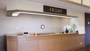 Un comptoir d’accueil avec une pancarte indiquant « RÉCEPTION », une horloge et un petit arrangement floral.