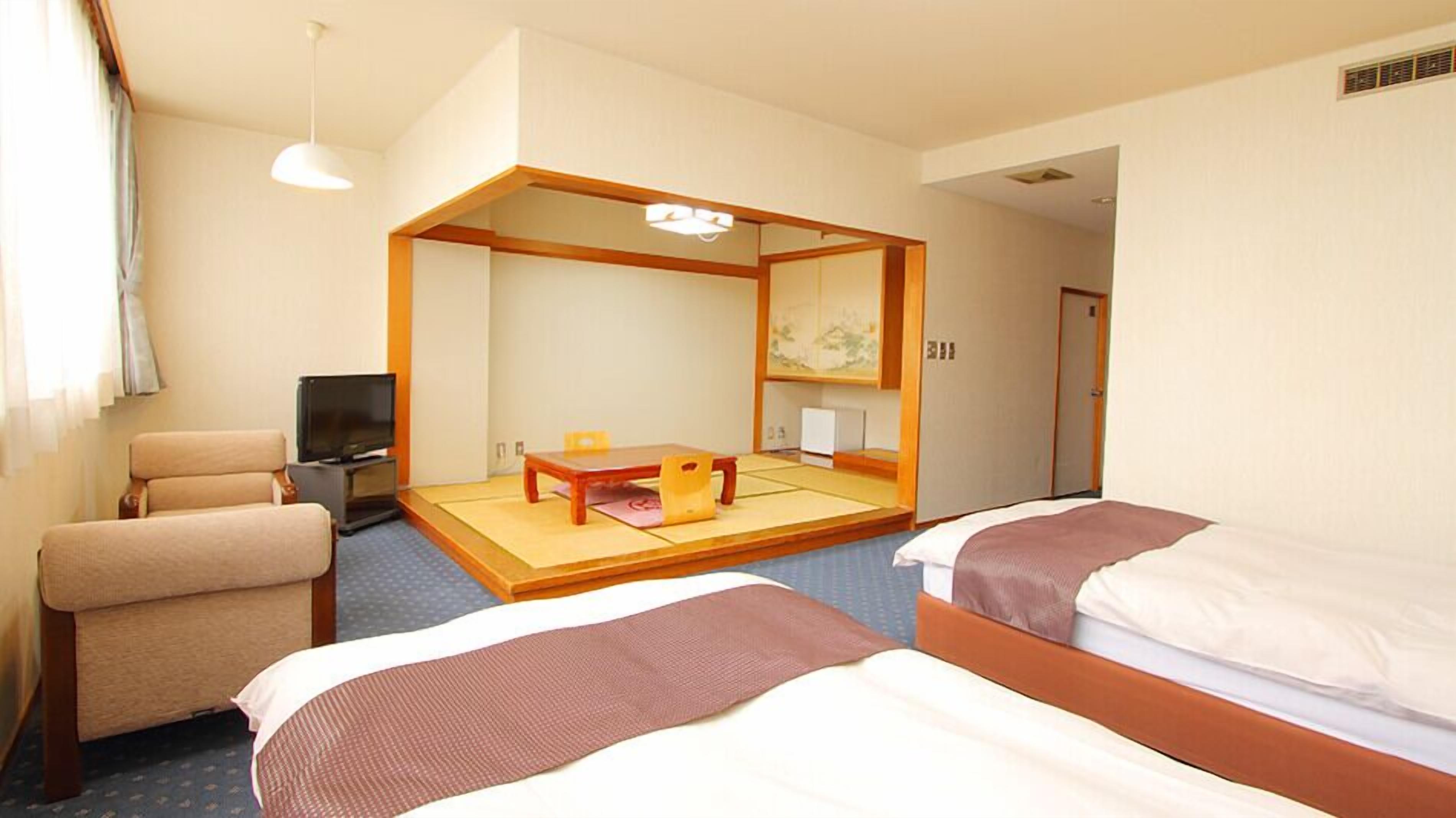 Une chambre d’hôtel avec un lit, une chaise, une petite table, un téléviseur et un miroir.