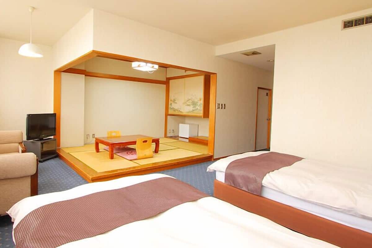 Une chambre d’hôtel avec un lit, une chaise, une petite table, un téléviseur et un miroir.