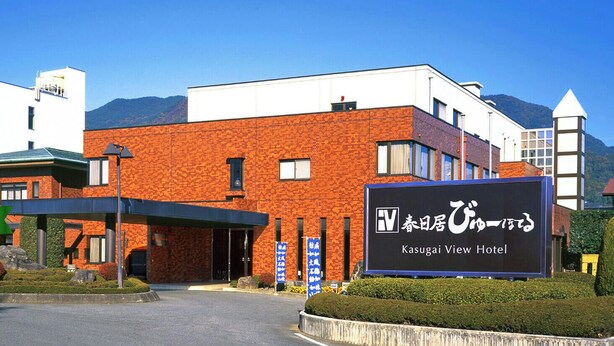 A hotel with a brick facade, a covered entrance, and a signboard with Japanese text. - Fujisan Isawa Onsenkyo Kasugai View Hotel (Fuefuki)