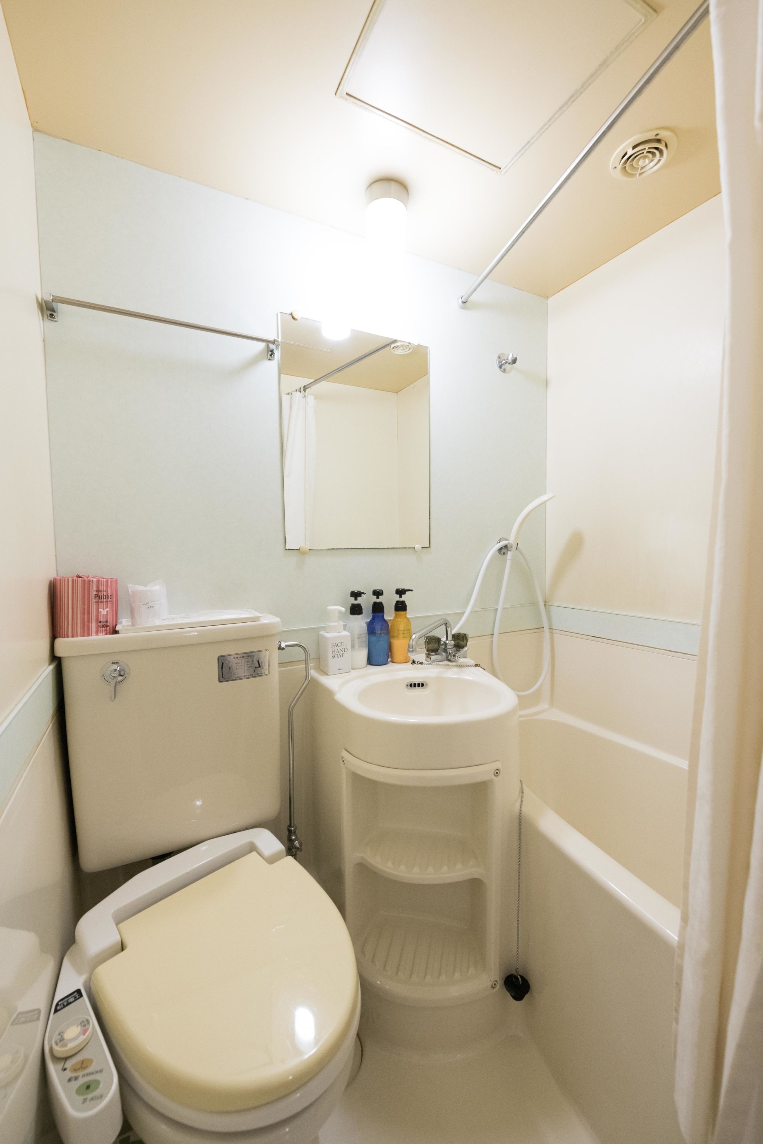 A compact bathroom with a toilet, sink, and shower.