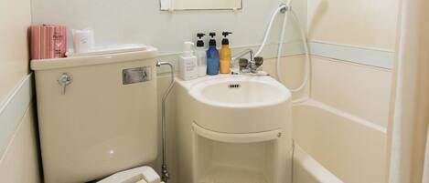A compact bathroom with a toilet, sink, and shower.