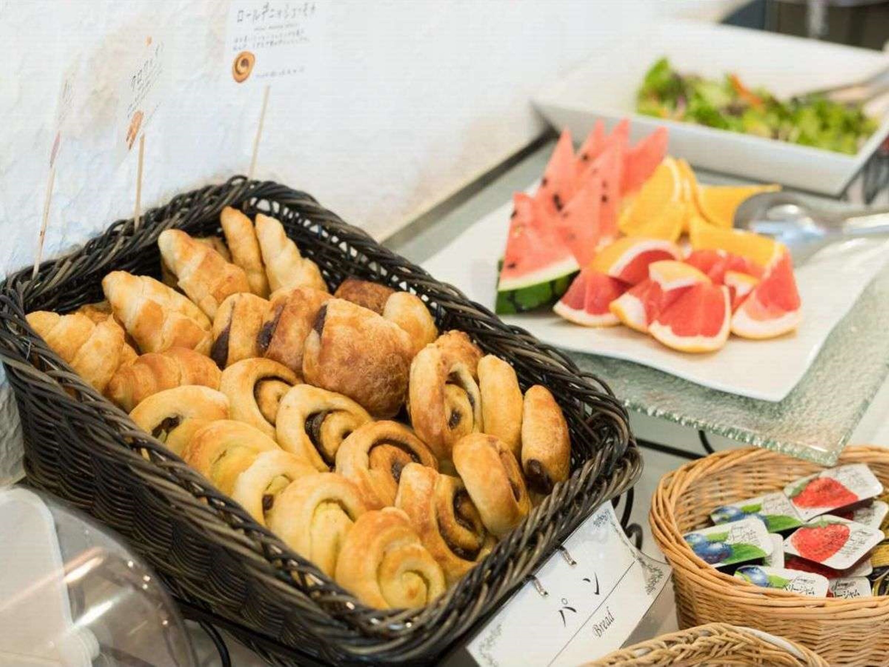 A buffet table with a variety of baked goods, fresh fruits, and packaged snacks.
