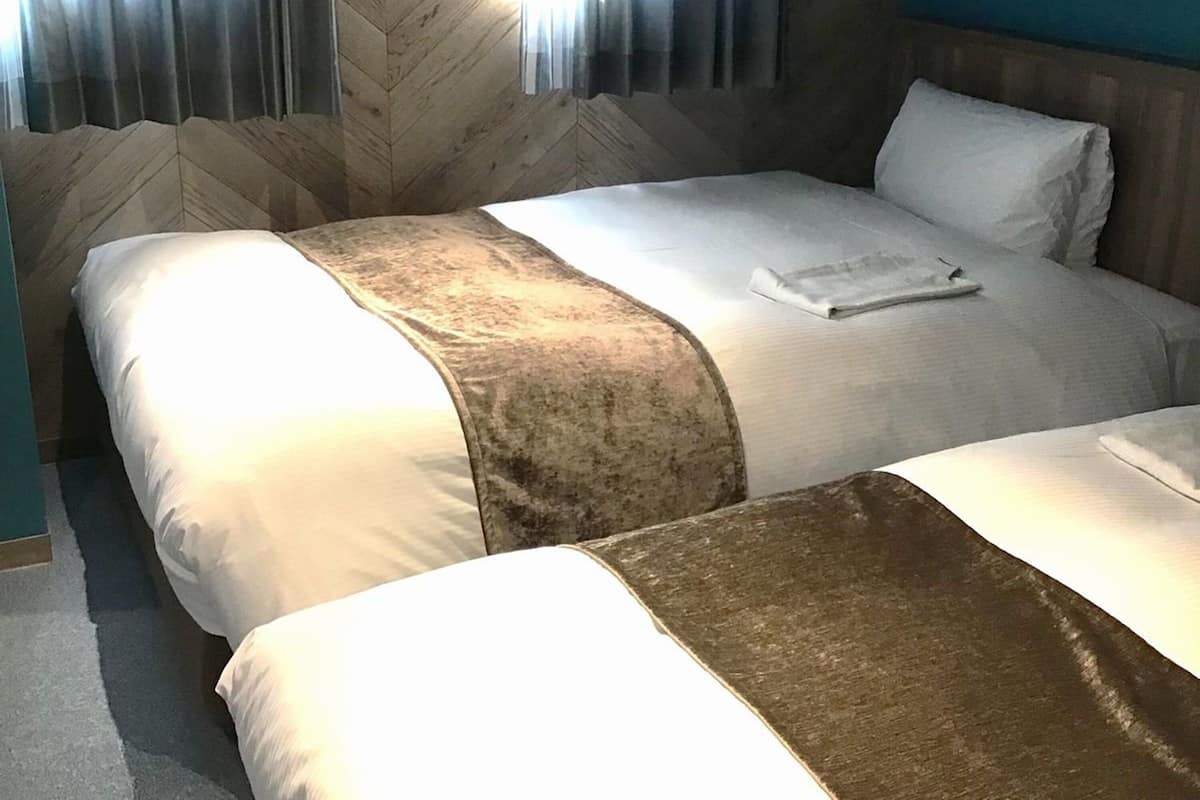 A hotel room with two beds, a wooden headboard, and a window with curtains.