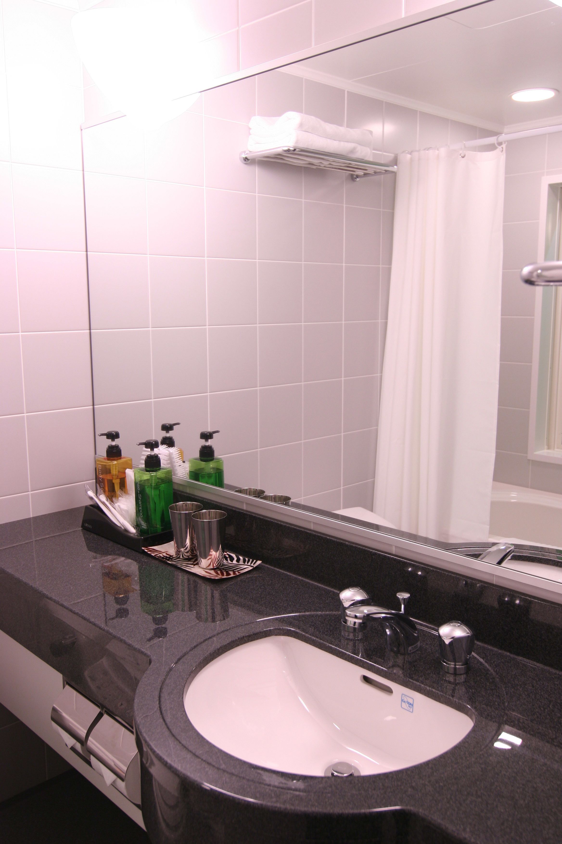 Un baño con lavamanos, espejo y artículos de aseo.