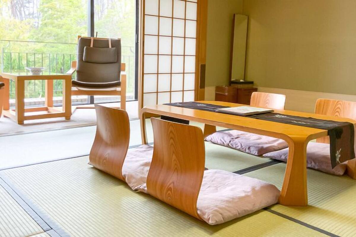 A traditional Japanese room with tatami flooring, a low table, and wooden furniture.