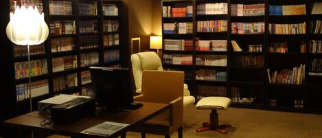 Una biblioteca con estanterías, un escritorio, una computadora y una silla.