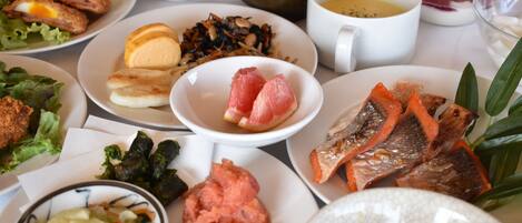 A table with various dishes including fried eggs, fish, and vegetables.