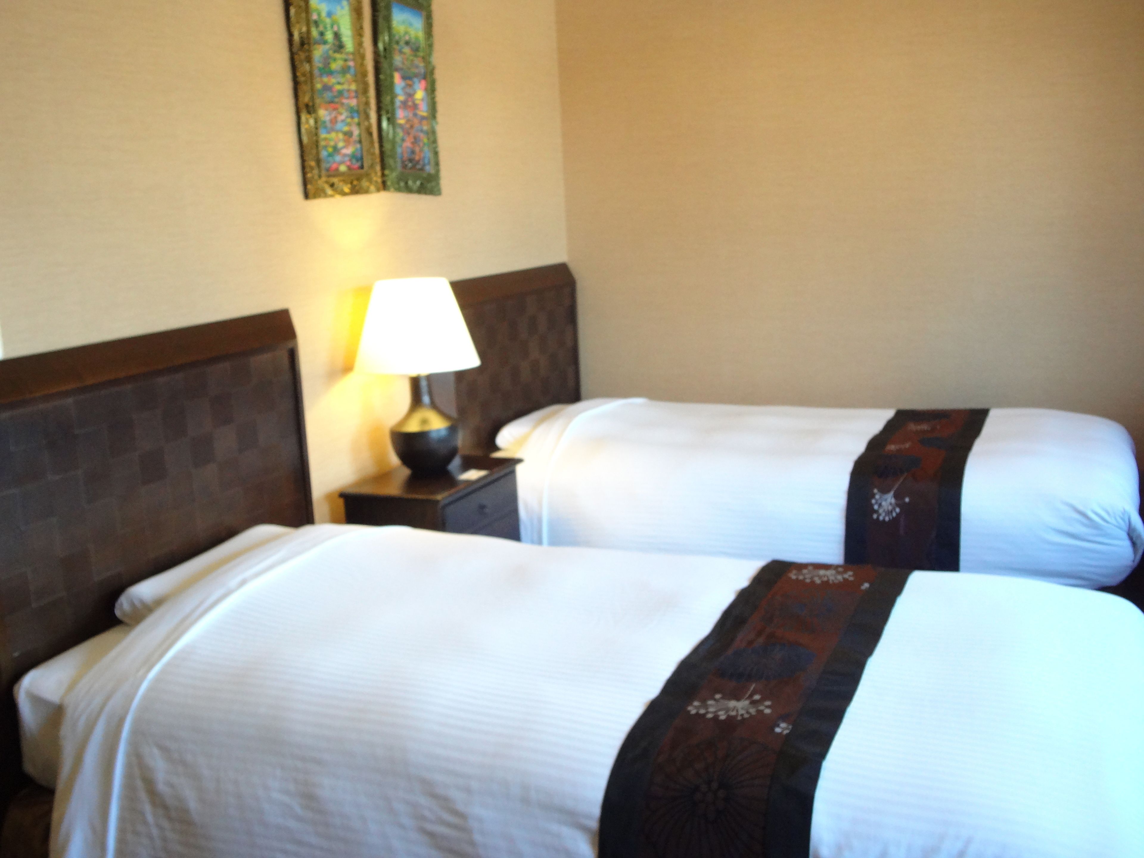 Two beds with white linens and dark headboards in a hotel room.