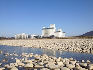 A hotel with multiple buildings, a rocky shoreline, and calm water. - Gifu Grand Hotel (Gifu)